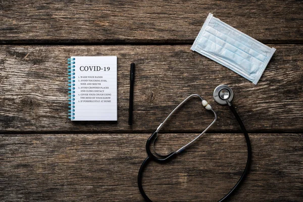 横に聴診器と医療保護マスクとノートパッドで書かれた手を洗うようなコヴィド19疫学予防規則 — ストック写真