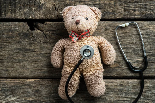素朴な木製の背景に置かれたテディベアのおもちゃの聴診器ディスク 小児医学の概念イメージ — ストック写真