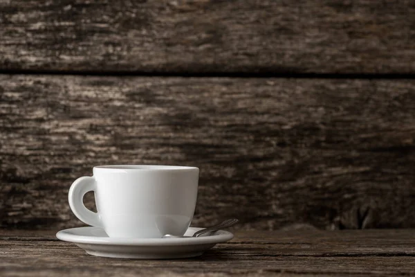 素朴な木の背景の上にスプーンでプレート上のコーヒーの白いカップ — ストック写真