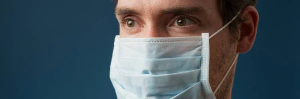 世界的なコロナウイルスの脅威の概念的なイメージで医療用保護マスクを身に着けている男の広い視野イメージ — ストック写真