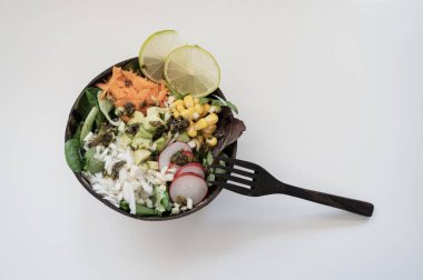 Hindistan cevizi Buda kasesinde servis edilen havuç, turp, mısır ve avokado ile karışık vejetaryen salatasının üst görüntüsü. Beyaz arkaplan.