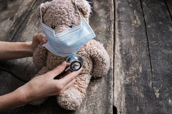 小儿保健的概念形象 带保护膜泰迪熊上的女性手持医用听诊器 — 图库照片
