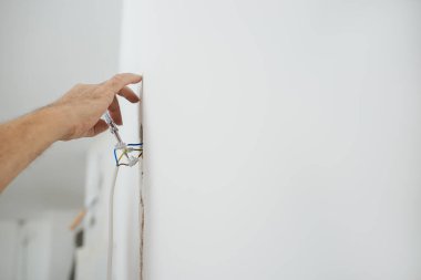 Elektrik akımını özel bir araçla kontrol eden elektrikçinin yakın görüntüsü. 