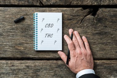 CBD ve THC yasallaştırma kavramsal imaj - not defterine THC ve CBD yazan bir avukatın eli.