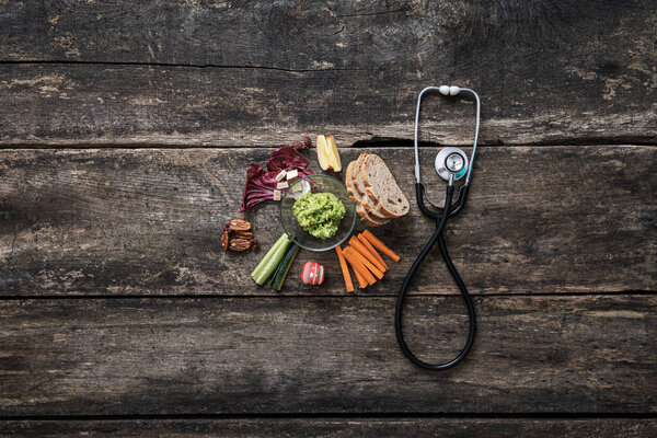 Conceptual image of healthy eating as care of ones health -  stethoscope next to a healthy vegan snack with avocado spread and raw veggies.