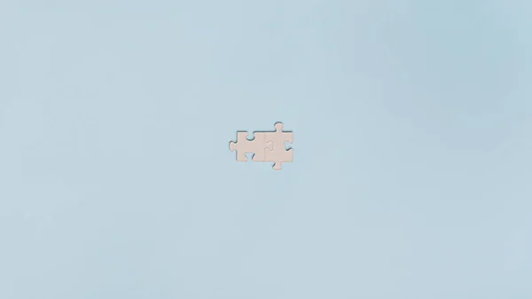 Two blank matching puzzle pieces placed over light blue background. With plenty of copy space.