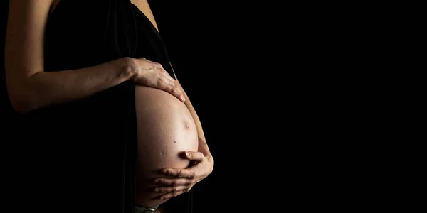 Closeup Pregnant Woman Holding Her Swollen Belly Standing Black Background Stock Picture