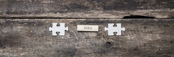 単語の広い表示画像2つの空白のパズルピースの間に木製のペグに書かれたアイデア イノベーションとアイデアの概念 — ストック写真