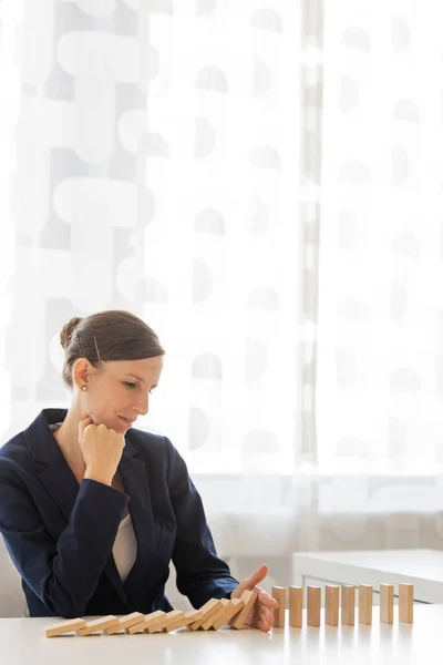 Young Businesswoman Sitting Her Office Desk Stopping Collapsing Dominos Her — Stock Photo, Image