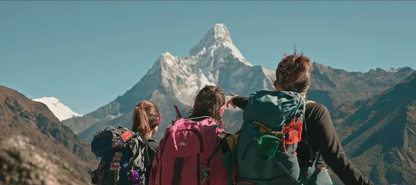Kızlar Everest Dağı 'nın tepesini işaret ediyor. Turistler ne tarafa gitmeleri gerektiğini görüyorlar.