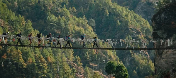 Turistler dağ köprüsünü geçiyor. Büyük bir çukurun üzerinde sallanmaktan.