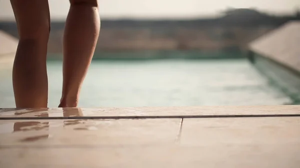 Kızın bacakları havuza iniyor. İtalya.