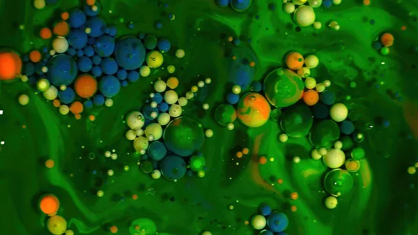 Multi-colored bubbles in the water. Abstract rainbow drops, can be used as background. Vividly beautiful this image is an abstract macro depiction. Still life cosmetics photography. Overhead top down. Green
