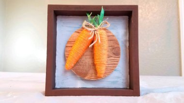 Bir çerçevede iki dekoratif havuç. İpten yapılmış havuçlar. Beyaz Tahta Arkaplanda İki Dekoratif Havuç