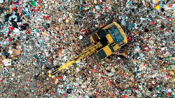 Tractor on a mountain of garbage. Tractor with a bucket on the garbage. Photo taken from above. Save the planet.