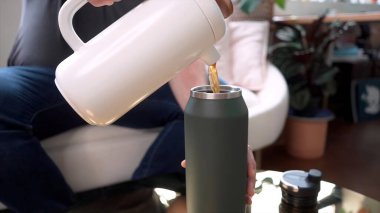 Termos. Tekrar kullanılabilir çelik termo su şişesini tutan erkek eli yakın plan..