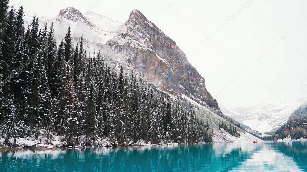 Blue lake and mountains. First snow Morning at Moraine Lake in Banff National Park Alberta Canada Snow-covered winter mountain lake in a winter atmosphere. Beautiful background photo.