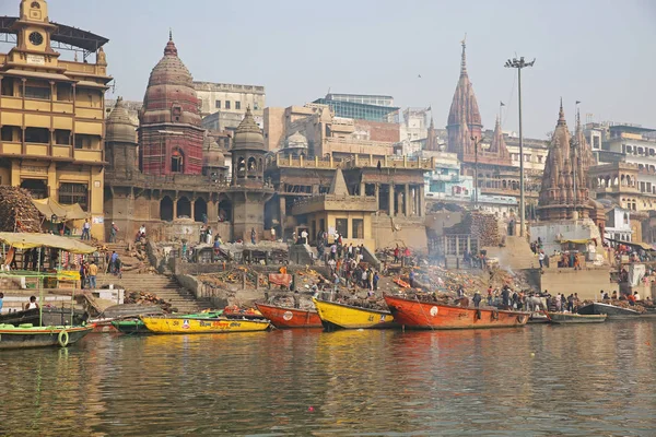火葬の火 ガンジス川 カラフルな船と高くそびえる寺院強化バラナシ インドの神聖なガンジス川に沿って火葬火災のシーン — ストック写真