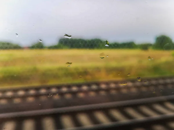雨は窓の後ろのレールと風景と旅行で電車の窓に落ちます — ストック写真