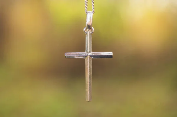 Stříbrný kříž na pozadí přírody. Koncept víry, spirituality a náboženství. — Stock fotografie