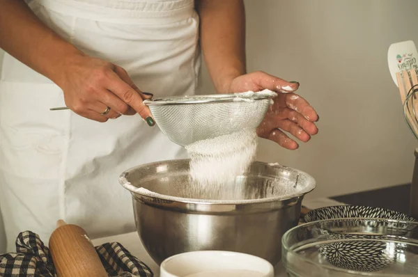 Vrouw voegt wat bloem toe aan het deeg op houten tafel. Vrouw handen kneden vers deeg. — Stockfoto