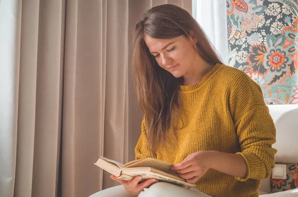 Wanita muda yang menarik membaca buku di rumah. Gadis bijaksana membaca buku penting — Stok Foto