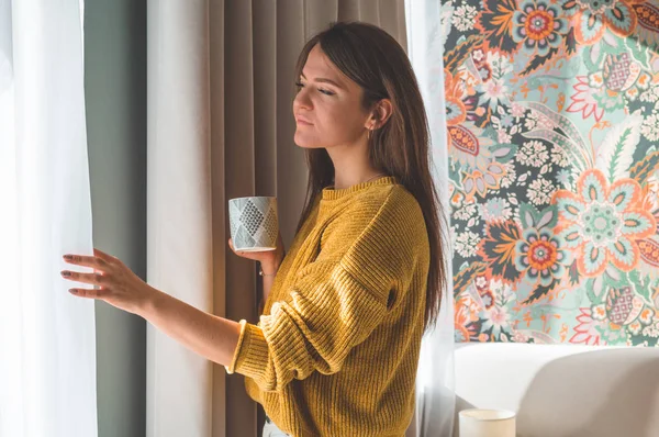 Женщина с чашкой горячего напитка у окна. Смотреть в окно и пить чай . — стоковое фото