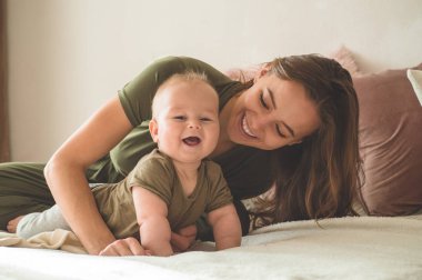 Yatakta annesi olan bir çocuğun ev portresi. Anne çocuğunu kucağına alıp öpüyor.. 