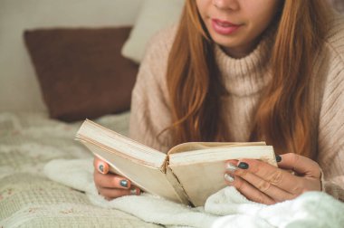 Çekici genç bayan evde bir kitap okuyor. Önemli bir kitap okuyan düşünceli bir kız..