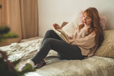 Çekici genç bayan evde bir kitap okuyor. Önemli bir kitap okuyan düşünceli bir kız..