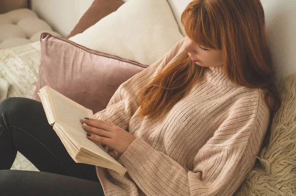 Uma jovem atraente está lendo um livro em casa. Menina pensativa lendo livro importante . — Fotografia de Stock