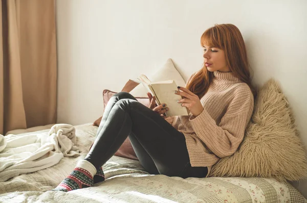 Uma jovem atraente está lendo um livro em casa. Menina pensativa lendo livro importante . — Fotografia de Stock