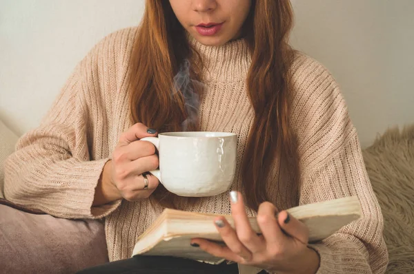 Een vrouw die hete thee drinkt en een boek leest. Ontwikkeling en ontspanning — Stockfoto