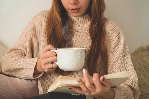 Mujer bebiendo té caliente y leyendo libro. Desarrollo y relajación — Foto de Stock