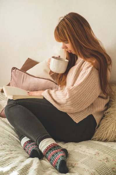 Mujer bebiendo té caliente y leyendo libro. Desarrollo y relajación — Foto de Stock