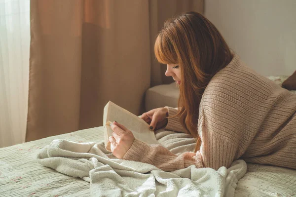 Una joven atractiva está leyendo un libro en casa. Chica reflexiva leyendo libro importante . — Foto de Stock