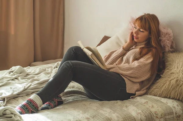 매력적 인 한 젊은 여자 가집에서 책을 읽고 있습니다. 중요 한 책을 읽는 사려깊은 소녀. — 스톡 사진