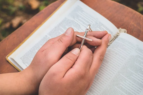 Kobieta trzymająca krzyż w ręku na tle Biblii — Zdjęcie stockowe