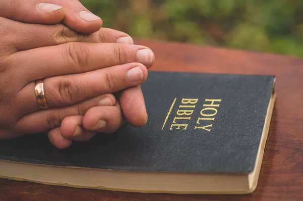 Kvinna som håller ett kors i handen mot bakgrund av Bibeln — Stockfoto