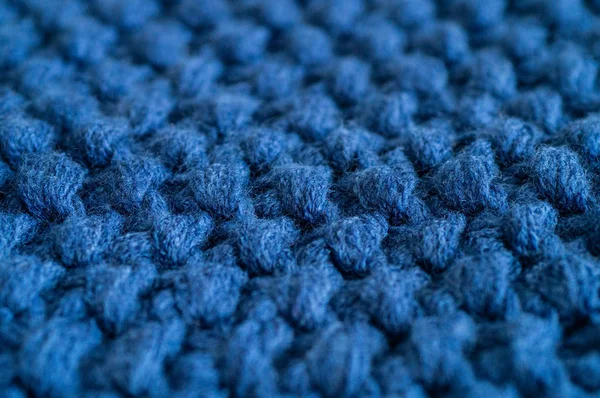 Warm knitted dark blue background. Knitted clothes, sweaters, knitwear, space for text.