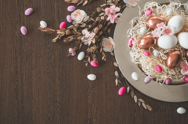 Feliz Pascua. Antecedentes de la Pascua de felicitación. Huevos de Pascua en un plato de metal con flores de primavera sobre un fondo de madera —  Fotos de Stock