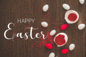 Veselé Velikonoce. Ploché kladení zlatých vajec a velikonoční červené posypky na dřevěném pozadí
