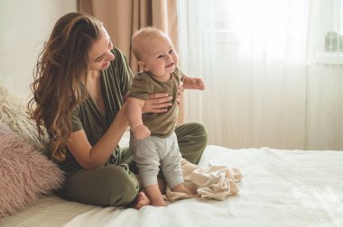 Yatakta annesi olan bir çocuğun ev portresi. Anne çocuğunu kucağına alıp öpüyor. İlk Adımlar.