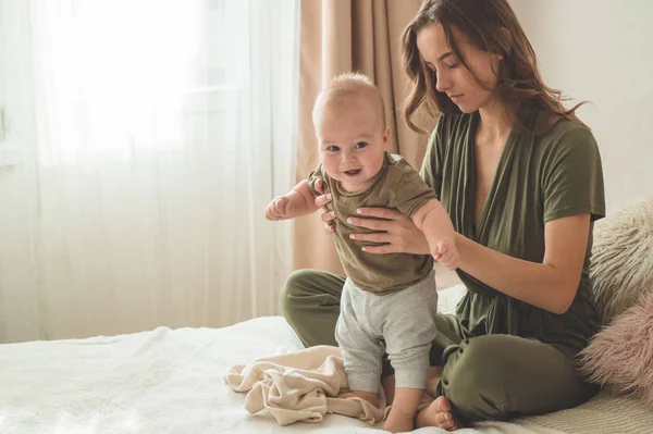 Portret chłopca z matką na łóżku. Mama trzyma i całuje swoje dziecko. Pierwsze kroki. — Zdjęcie stockowe