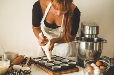 Güzel kızıl saçlı kız pasta şefi kek pişiriyor. Un ürünleri veya tatlı için konsept malzemeler. 