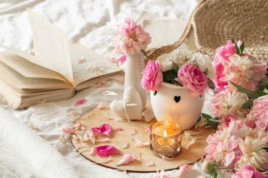 Mum ve vazo, güller ve şakayıklar, çiçekler ve kitaplarda bahar dekoru.