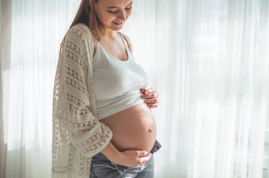 Pencerenin kenarındaki koca göbekli mutlu hamile kadın. Hamilelik ve aile kavramları