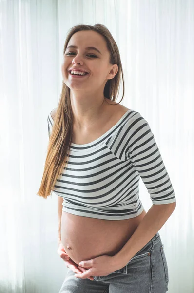 Mulher grávida feliz com barriga grande pela janela. Conceitos de gravidez e família — Fotografia de Stock