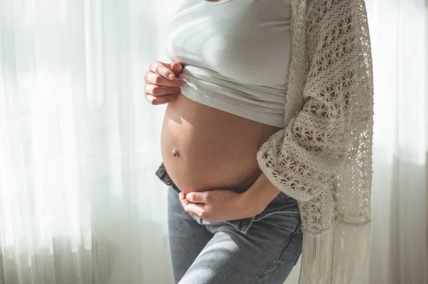 Heureuse femme enceinte avec un gros ventre près de la fenêtre. Concepts de grossesse et de famille — Photo