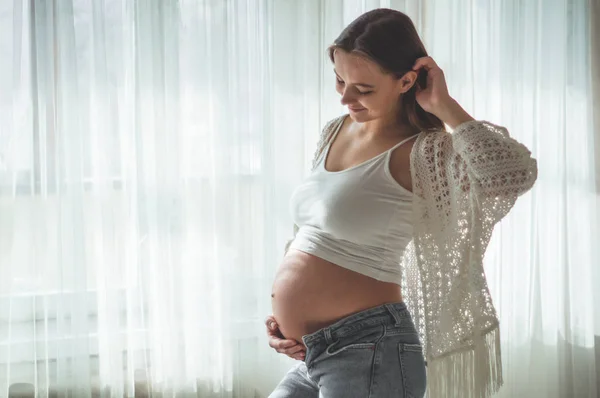 Mulher grávida feliz com barriga grande pela janela. Conceitos de gravidez e família — Fotografia de Stock